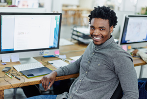 Young man sitting infront of his computer smiling